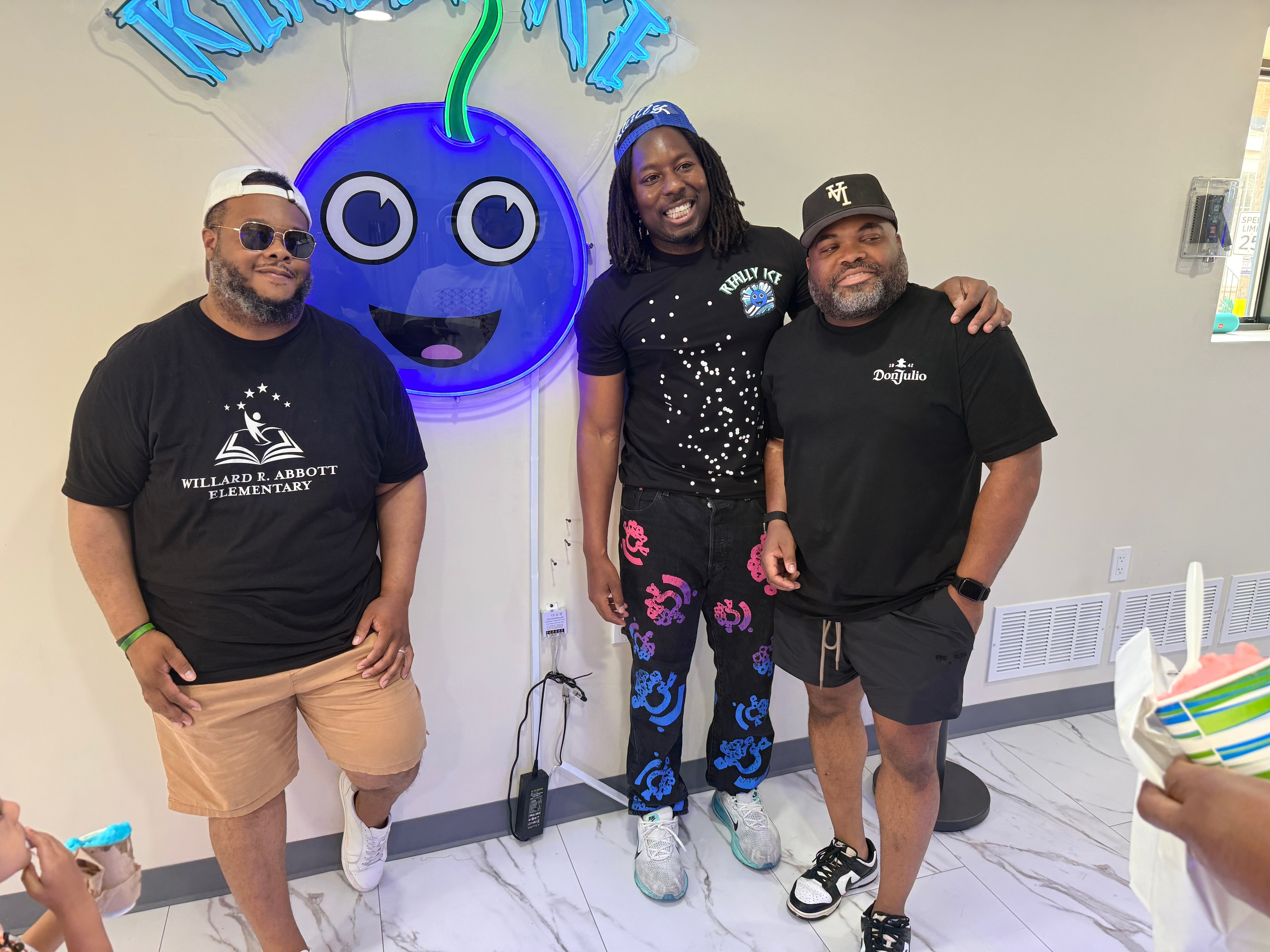 Dean Owens with a Willard R. Abbott Elementary school rep and a guest in front of the Really Ice mascot logo
