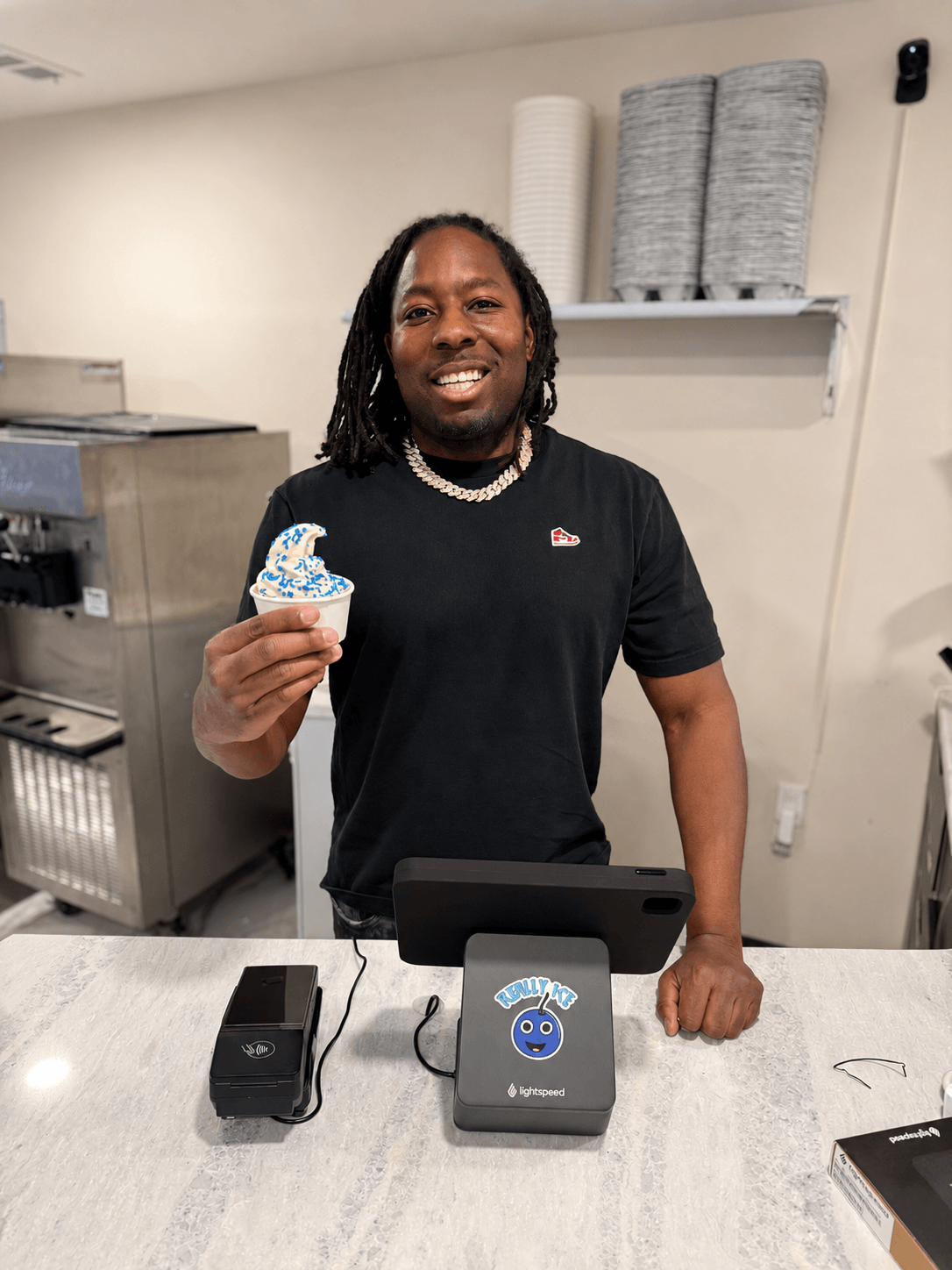 Dean Owens behind the Really Ice counter holding a brand sticker